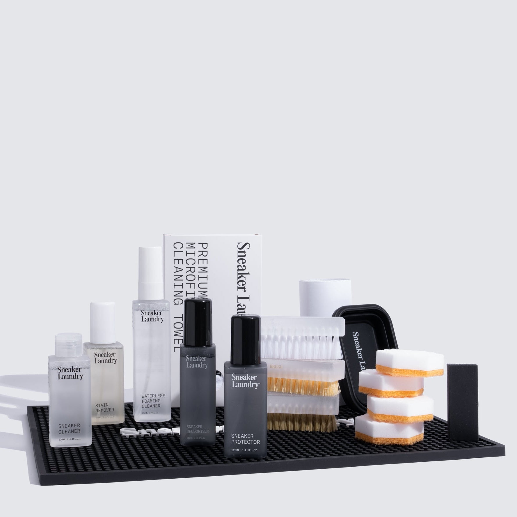 Collection of sneaker cleaning products on a black tray with a white background